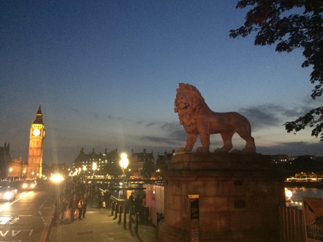 A lion statue sits on one end of a bridge with Big Ben in the background