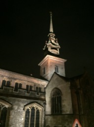 The spire of a church lit from below in sharp contrast to the night sky