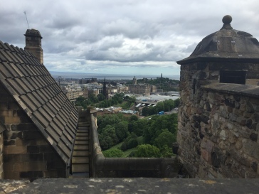 Edinburgh sits in the distance between stone buildings in Edinburgh Castle