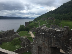 The courtyard and ruined buildings of Urquhart Castle with Loch Ness in the background
