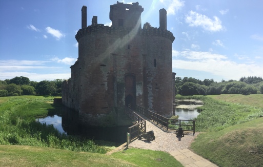 The moat and bridge leading to the gatehouse of Caerlaverock Castle on a sunny day