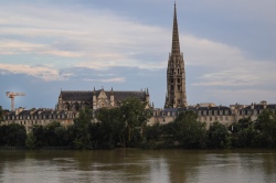 A cathedral and spire in Bordeaux behind the river