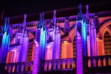 The buttresses of the Cathedral of Our Lady in Bayeux lit in orange, blue, and purple at night
